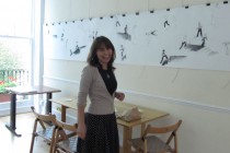 Laura Lazar in front of the exhibition's frieze drawing 
