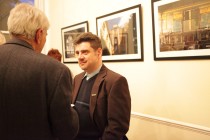 Members of the audience during the after-event reception. In the background, photographs by Christian Binder with old synagogues of Transylvania
