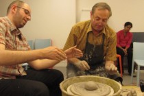 Mihai Risnoveanu gets guidance from Cornel Sitar on how to keep the clay from flying off the wheel